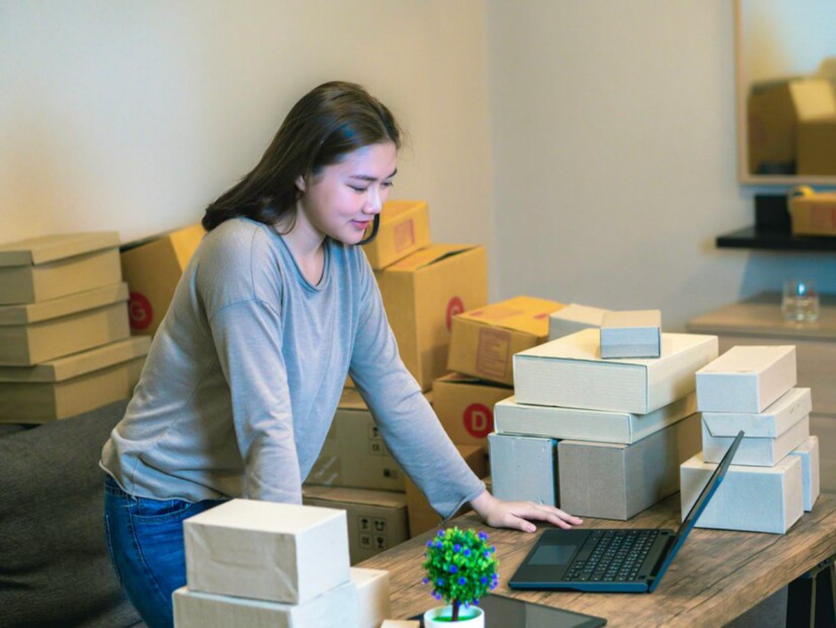 A woman managing inventory with a laptop in a small business warehouse.