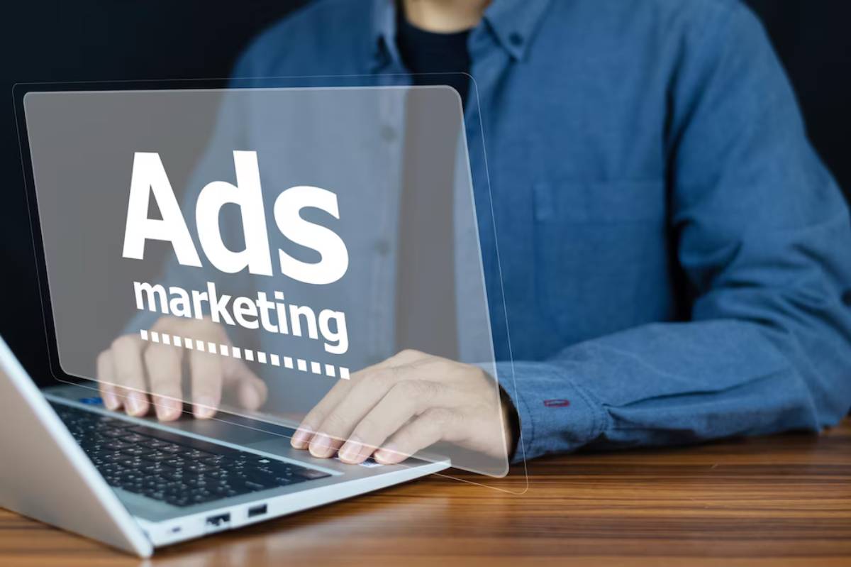 Person working on a laptop with a transparent screen displaying Ads marketing in front of them.