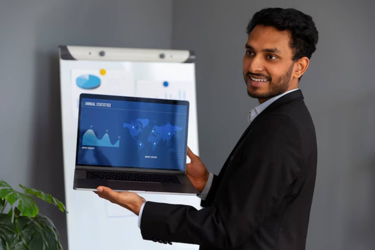 Businessman presenting annual statistics on a laptop screen in a modern office setting.