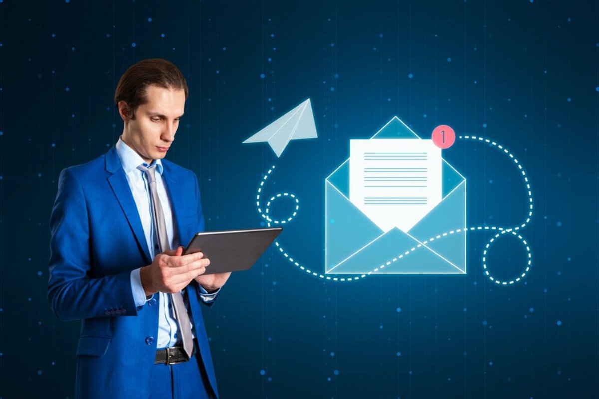 A man in a blue suit using a tablet with graphical email and paper plane icons on a digital background.