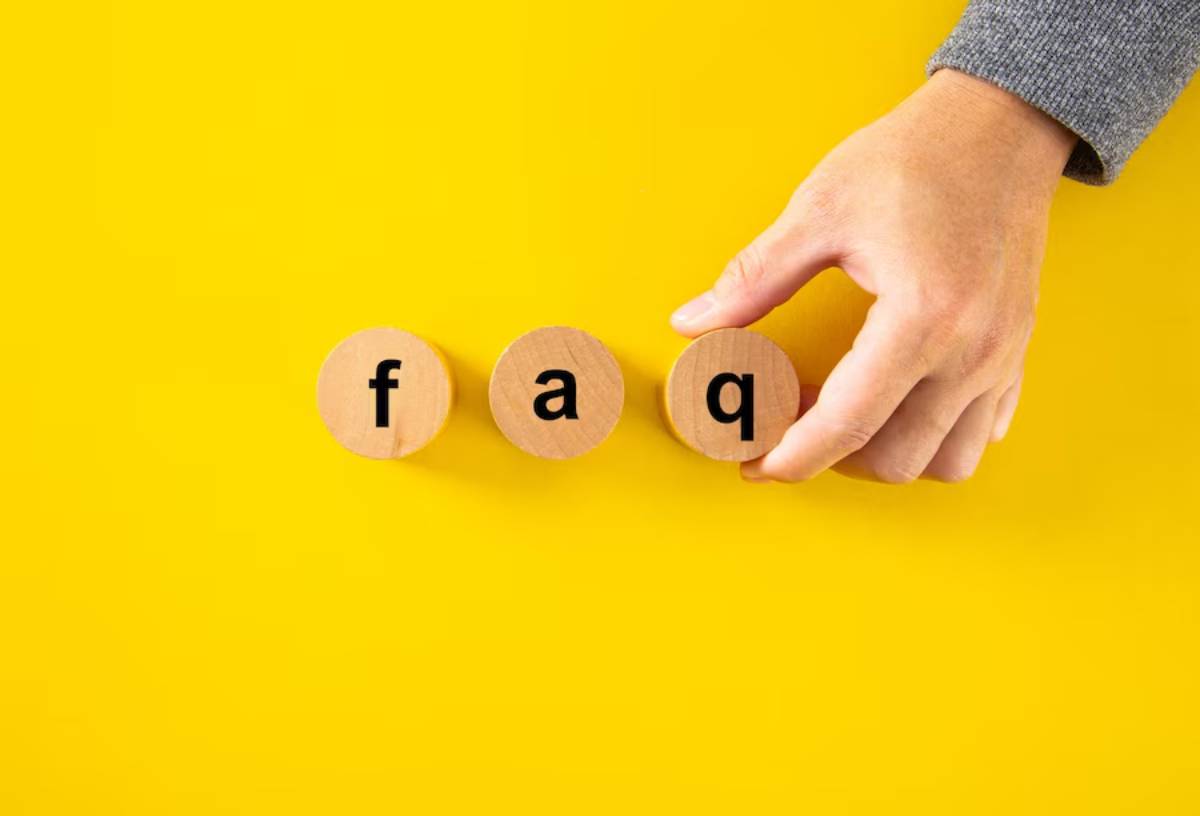 Hand arranging wooden disks with letters f, a, q on a bright yellow background.