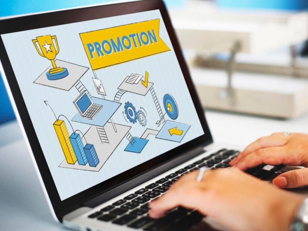 A person using a laptop displaying a colorful digital illustration of business tools marked with the word PROMOTION.