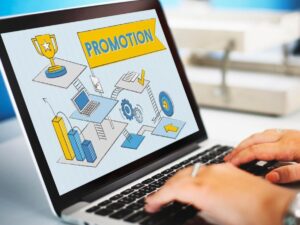 A person using a laptop displaying a colorful digital illustration of business tools marked with the word PROMOTION.