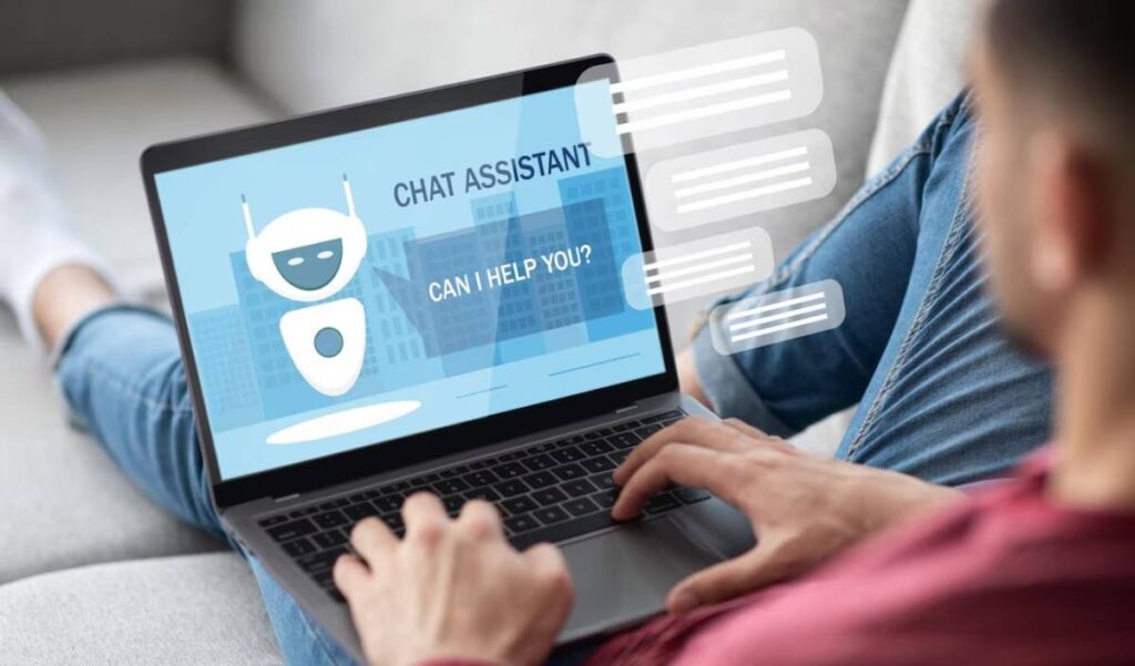 Man using a laptop displaying a chatbot interface, asking if it can help.