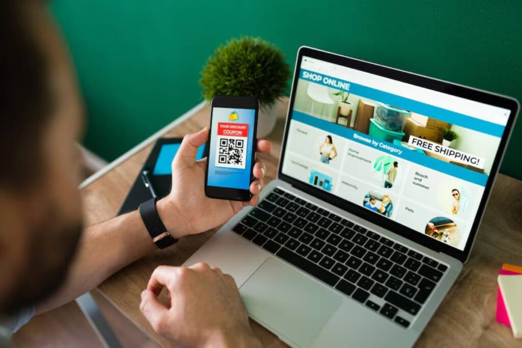 Man scans QR code on phone for a discount, with online shopping site open on laptop.